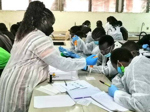 A scientist assisting students with a scientific experiment